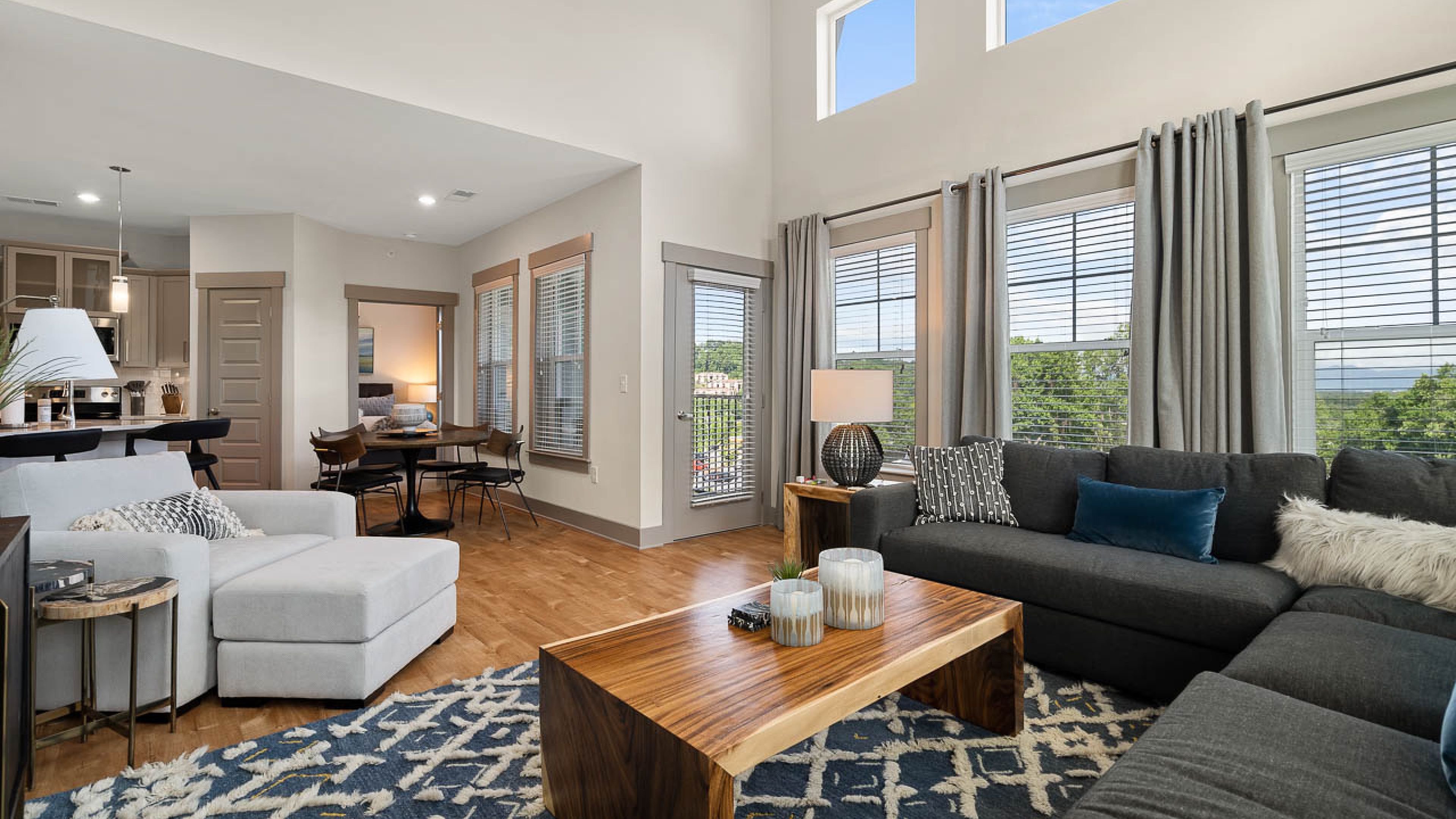 Hawthorne at Mills Gap apartment living room with large windows and high ceilings, furnished with a couch, coffee table, and chair